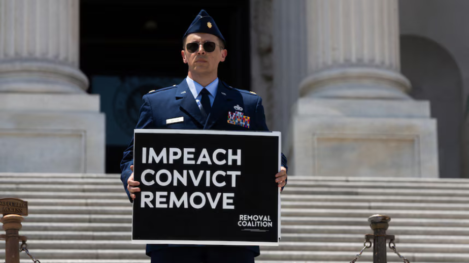 Major Jason Watson holding an Impeach Convict Remove sign on the steps of the U.S. Capitol.